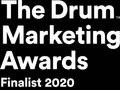 A person presenting an award on stage at the Drum Marketing Awards 2020, with a large backdrop displaying the event name and tagline.