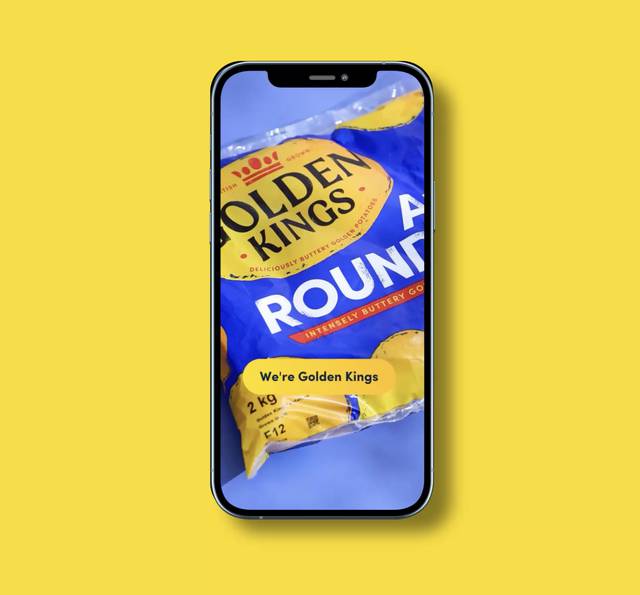 A smartphone displaying a bag of Golden Kings potato chips on a blue surface, with a yellow background. The screen shows a message: "We're Golden Kings."