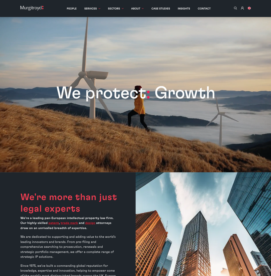 A person walking on a grassy hill near wind turbines while a cloudy sky looms in the background.