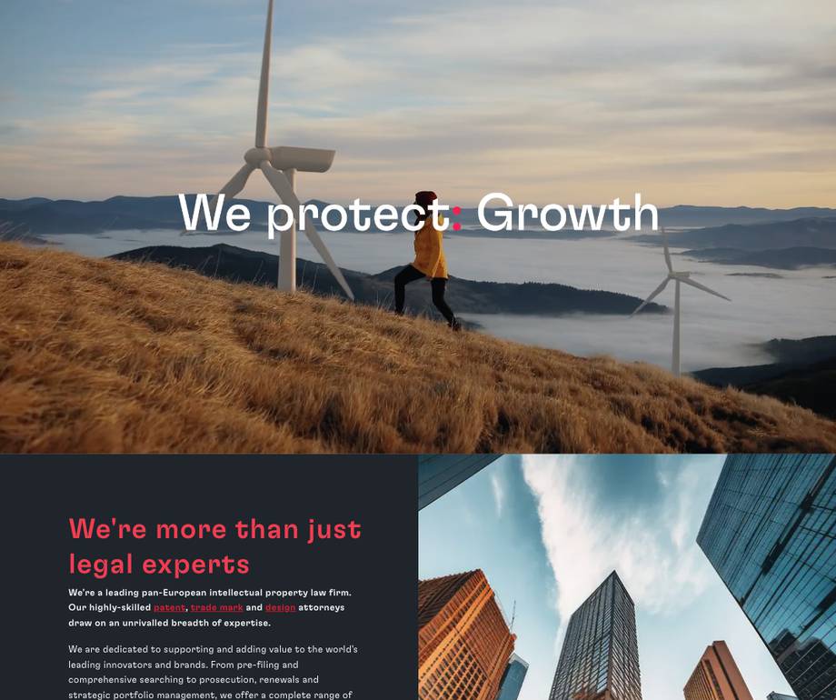 A person walking on a grassy hill near wind turbines while a cloudy sky looms in the background.