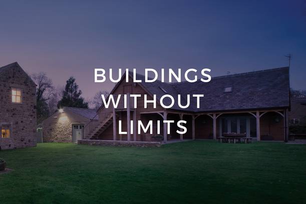 A stone and wooden building with a grassy lawn in front under a twilight sky, with the text "Buildings Without Limits" overlayed in white.