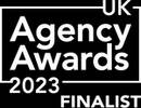 A person holding a trophy in front of a bright backdrop with "Agency Awards 2023 Finalist" text, celebrating success at an awards event.