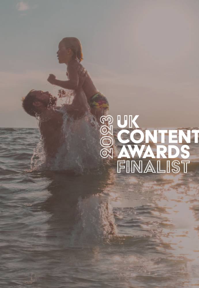 A person holding a child above water during sunset, with text indicating they are a finalist in the 2023 UK Content Awards.