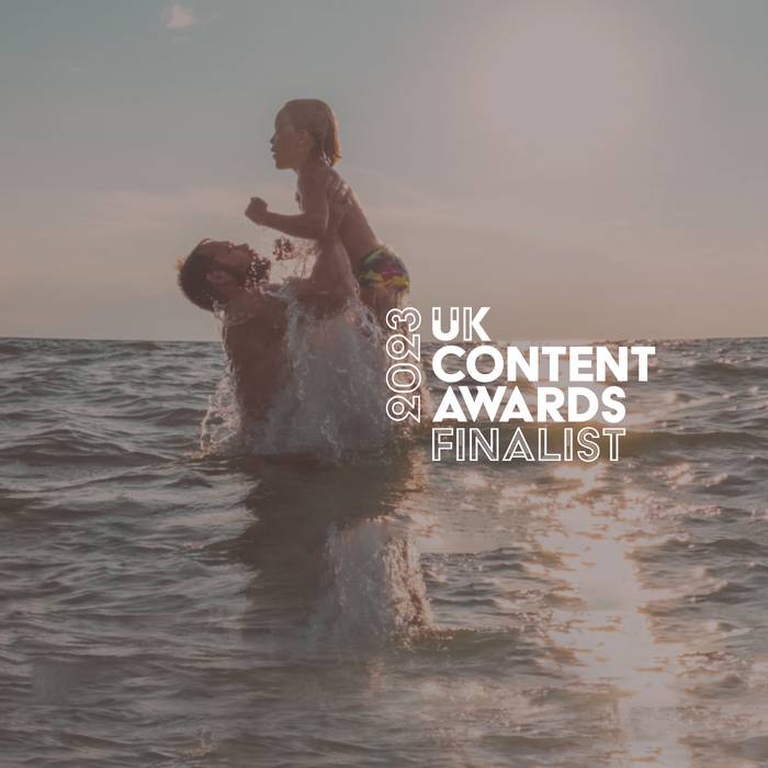 A person holding a child above water during sunset, with text indicating they are a finalist in the 2023 UK Content Awards.