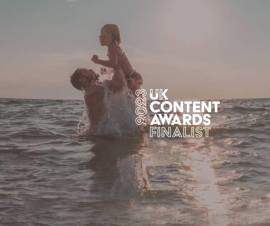 A person holding a child above water during sunset, with text indicating they are a finalist in the 2023 UK Content Awards.