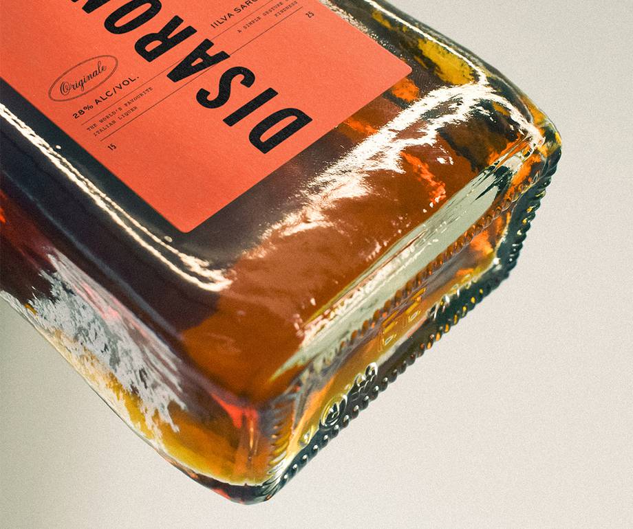 Close-up of a glass bottle with an orange label, positioned at an angle, with the label reading "DISA PARON." The bottle is against a neutral background.