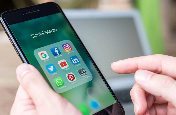 A person holding an iphone and browsing the apps