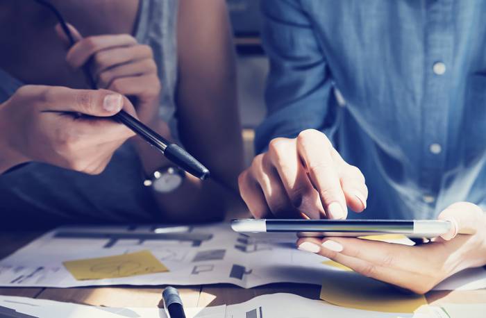 Two people looking at an ipad in conversation