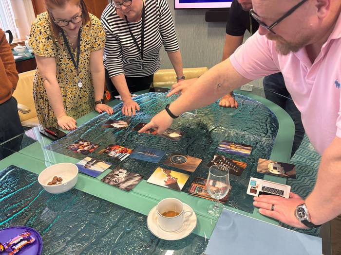 A team engaged in a brand strategy workshop hosted by Extreme, collaboratively analysing visual cards on a glass table.