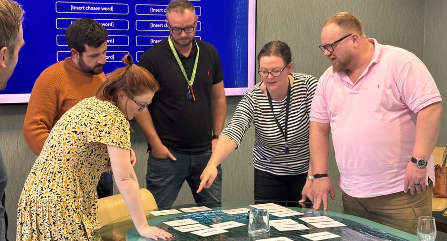 Participants in a brand strategy workshop discussing and selecting attributes, with a "Brand Personality" screen in the background.