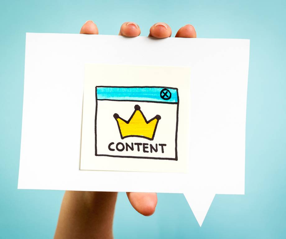 Hand holding a paper with a colourful illustration of a web browser window showing a yellow crown and the word "CONTENT".