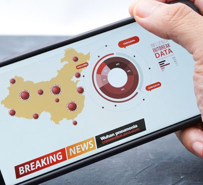 A hand holding a smartphone displaying a map of China with red virus icons, a circular chart, and news headline about Wuhan pneumonia and outbreak data.