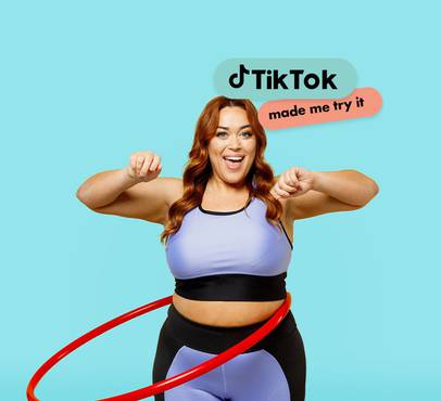 A woman with red hair wearing workout clothes, smiling and flexing her arms, with the TikTok logo and "made me try it" text above her.
