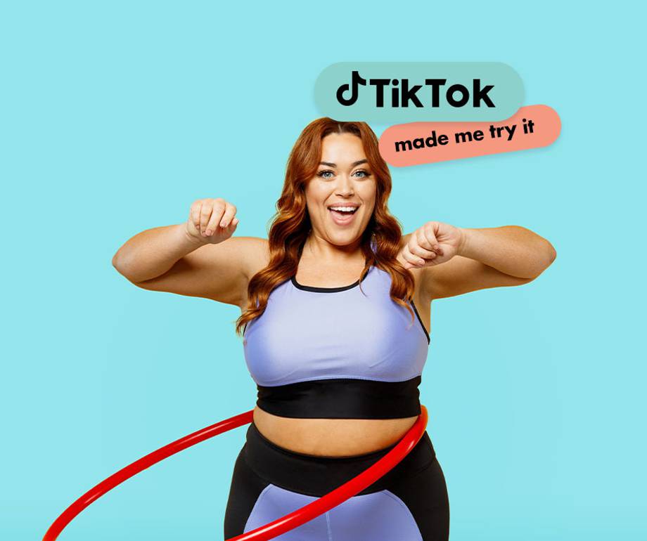 A woman with red hair wearing workout clothes, smiling and flexing her arms, with the TikTok logo and "made me try it" text above her.