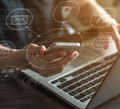 Person holding a smartphone above a laptop with digital network icons overlaying the image.