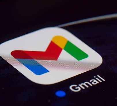 Gmail app icon on a dark smartphone screen, showing the red, blue, yellow and green stylised M logo on a white rounded square, with the "Gmail" label beneath it.