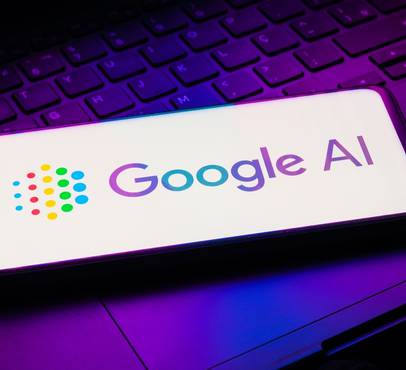 A smartphone displaying the Google AI logo, placed on a keyboard illuminated with purple and pink lights.