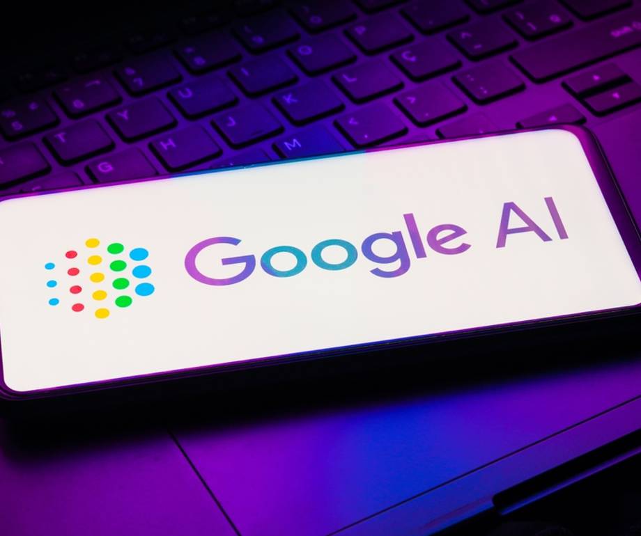 A smartphone displaying the Google AI logo, placed on a keyboard illuminated with purple and pink lights.