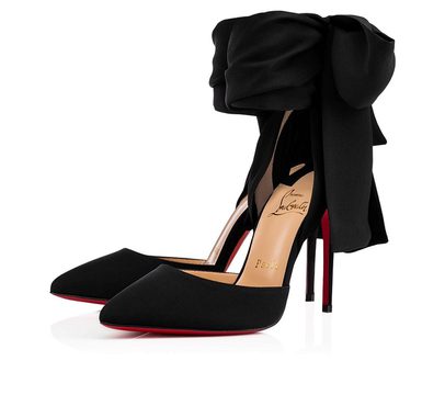 Black high-heeled shoes with red soles, decorated with a large black bow on top, displayed against a white background.