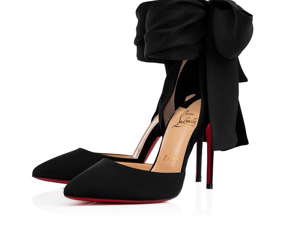 Black high-heeled shoes with red soles, decorated with a large black bow on top, displayed against a white background.