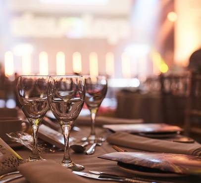 Empty wine glasses on a decorated dining table in a softly lit restaurant setting.