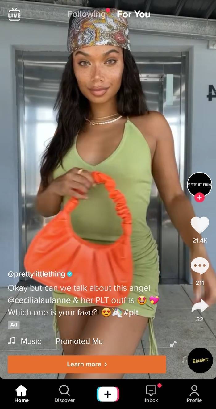 A screenshot of a woman modelling an orange bag for fashion brand Pretty Little Thing, as an advert on TikTok.