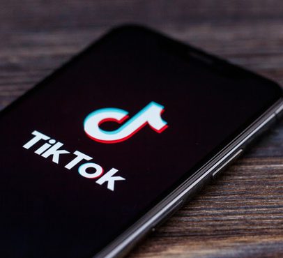 Smartphone displaying the TikTok logo on a wooden surface.