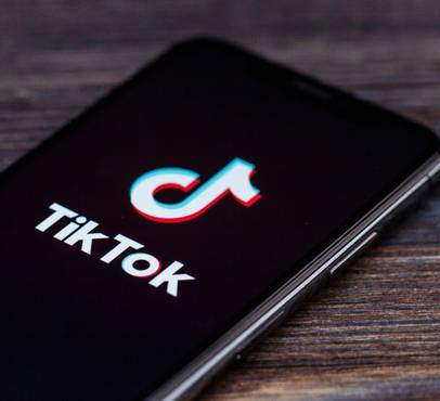 Smartphone displaying the TikTok logo on a wooden surface.