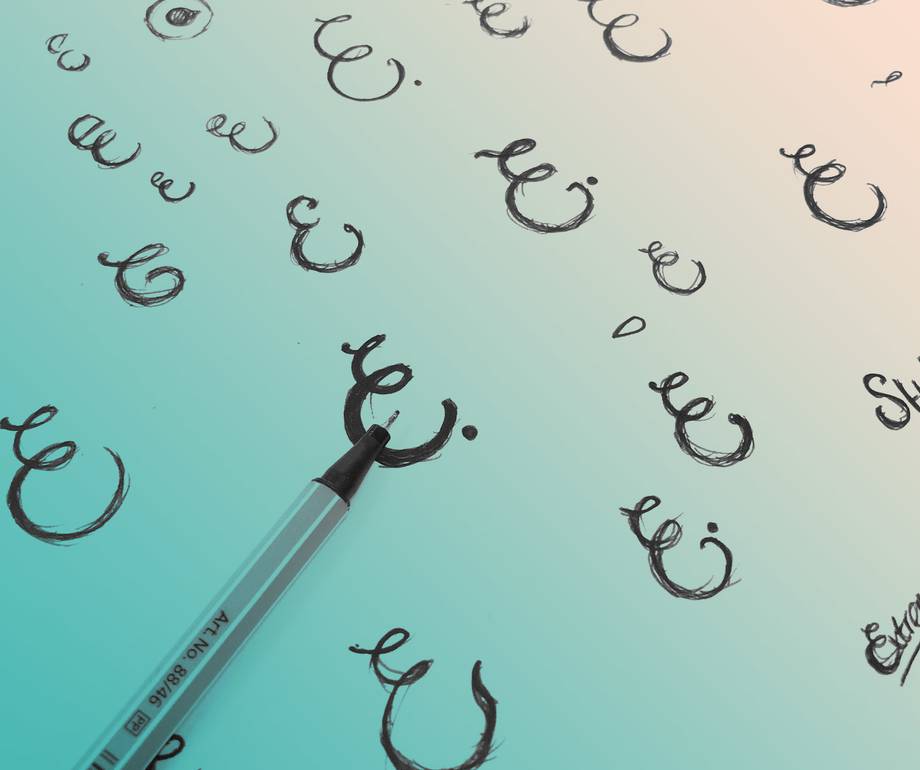 Black scribbles drawn with a pen on a white paper, with some words partially visible, placed on a light, smooth surface.