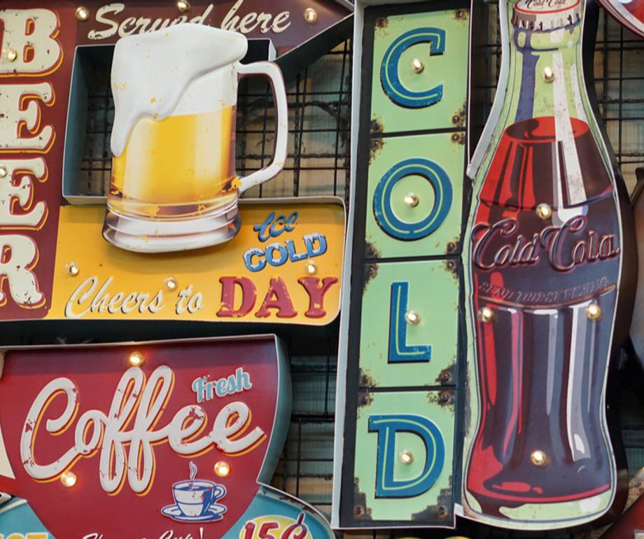 A collection of vintage-style neon signs advertising beer, coffee, soda, and cola, arranged on a display grid.