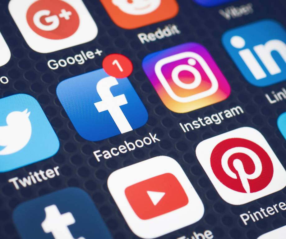 Close-up of a smartphone screen displaying social media app icons, including Facebook, Instagram, Twitter, LinkedIn, Pinterest, and YouTube.