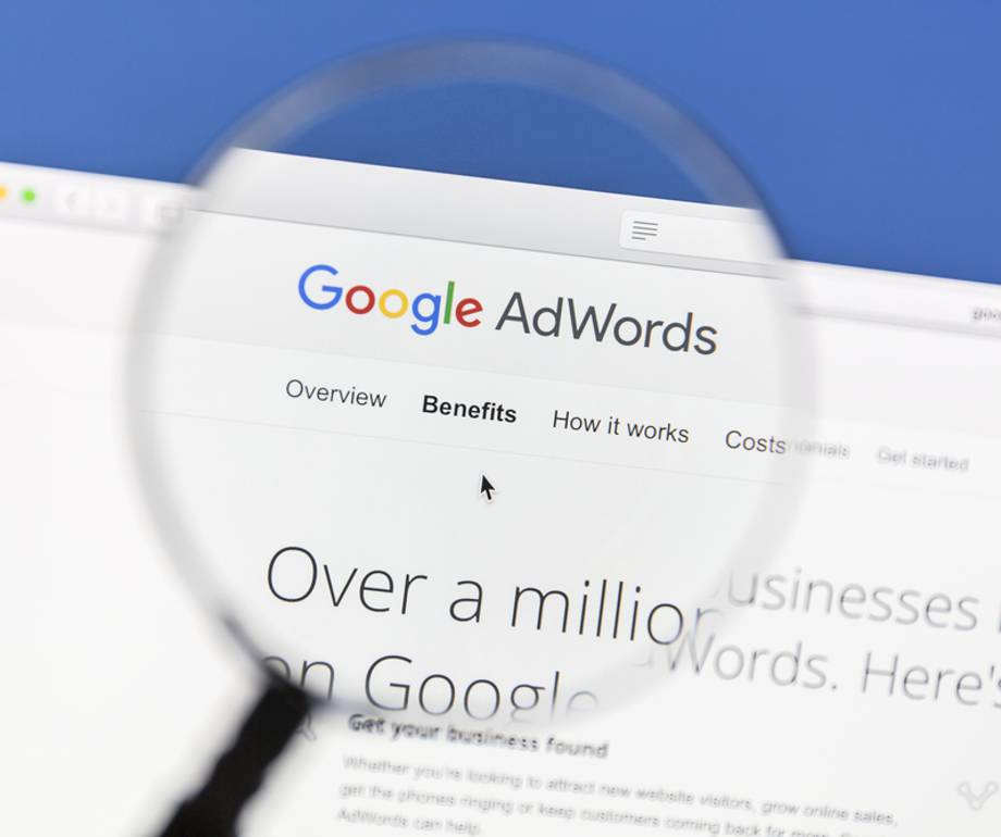 Close-up of a computer screen displaying the Google AdWords website through a magnifying glass.