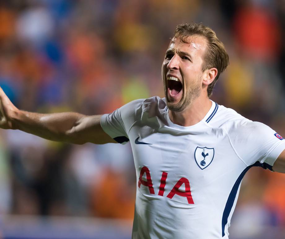 Football player wearing a white Tottenham Hotspur jersey celebrating with arms outstretched on the pitch.