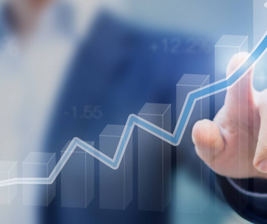 A person in a business suit touching an upward trending digital line graph, representing growth or success.