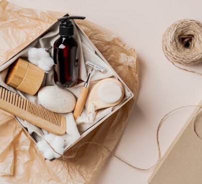 A collection of toiletries and grooming items, including a pump bottle, comb, natural sponges, and a roll of twine, arranged in a box with tissue paper.