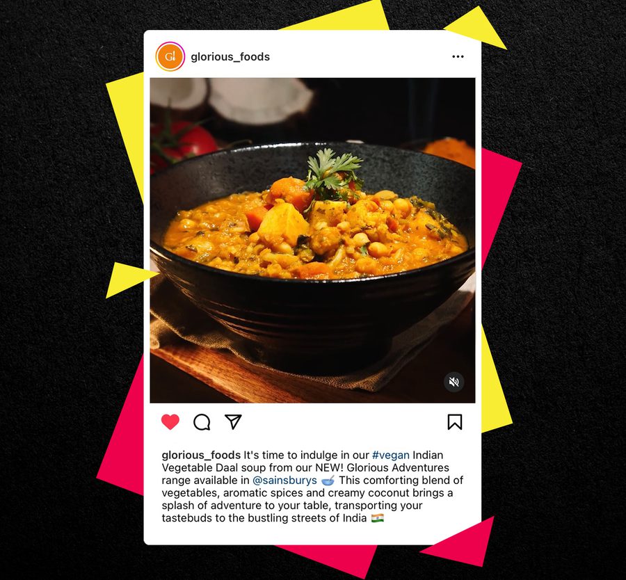 A bowl of vegan Indian vegetable dahl soup garnished with herbs, placed on a wooden surface with a dark background.