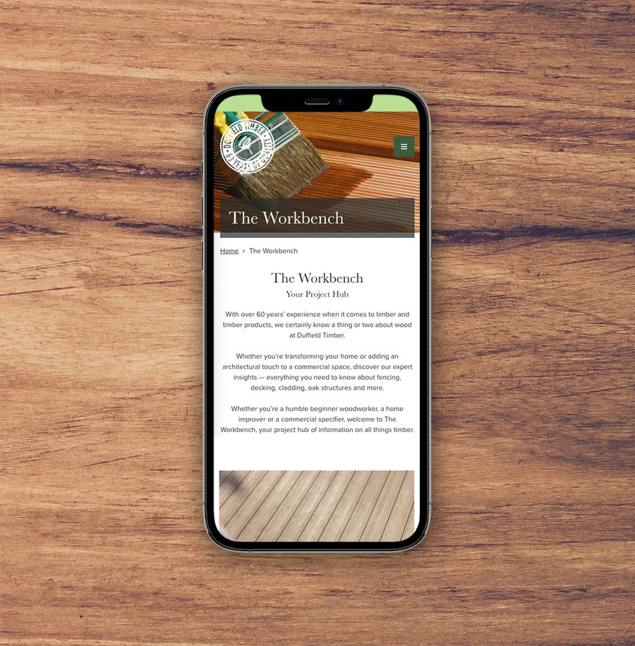 A smartphone displaying a webpage titled "The Workbench" on a wooden surface.