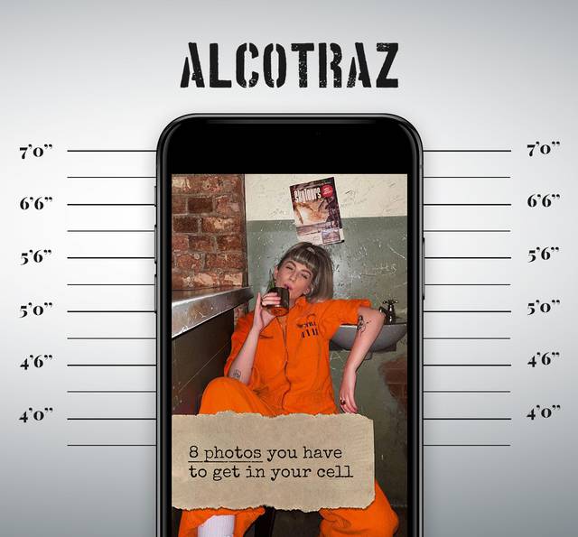 A woman in an orange jumpsuit sitting against a wall, drinking from a mug, with a mug shot-inspired background and height measurements on either side.