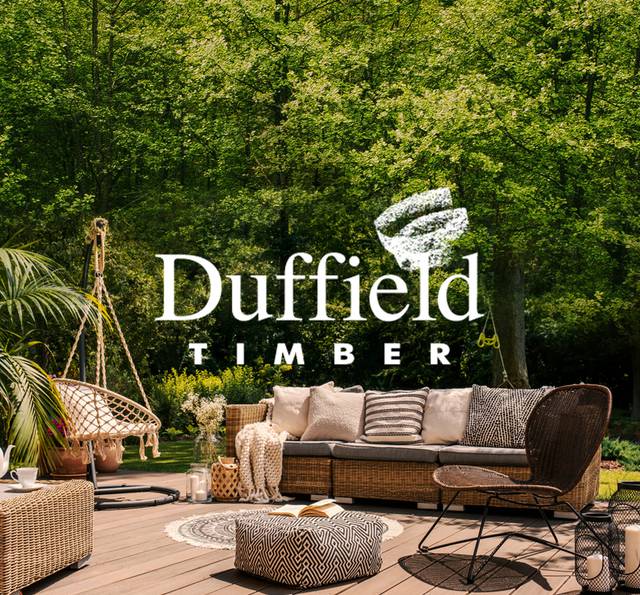 Sunlit timber decking with a wicker sofa, patterned pouffe and macramé hanging chair beneath lush trees, with the white Duffield Timber logo overlaid