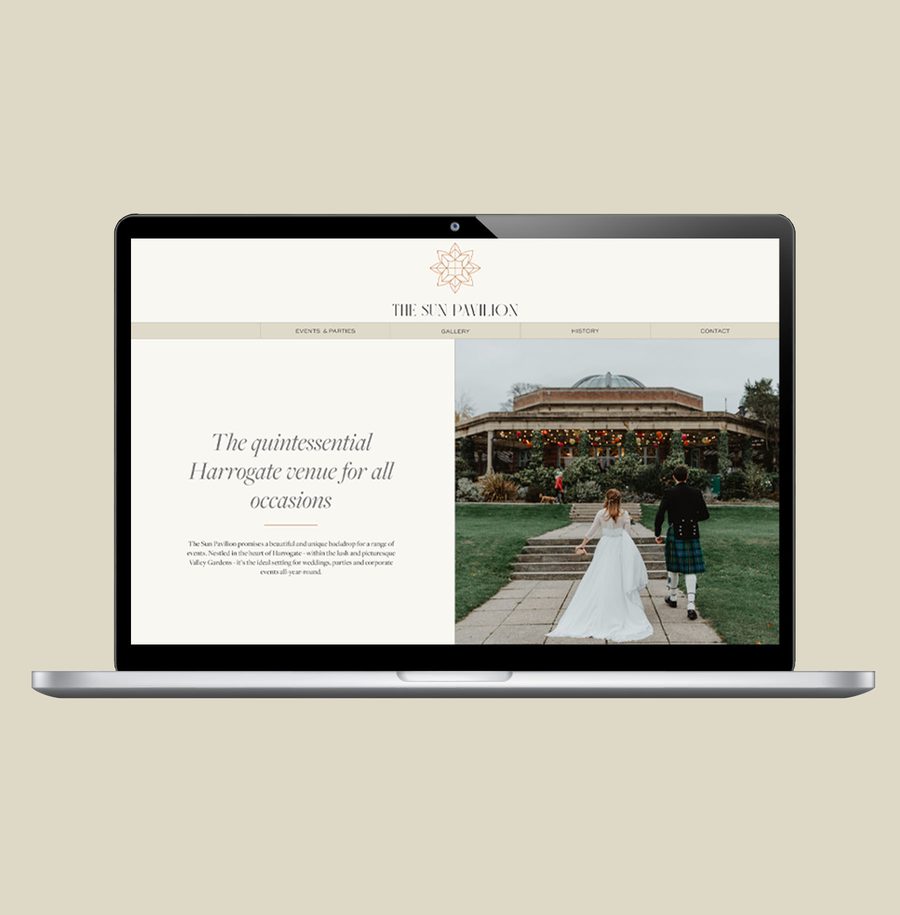 Laptop displaying a wedding venue website with a bride and groom walking towards a decorated building.