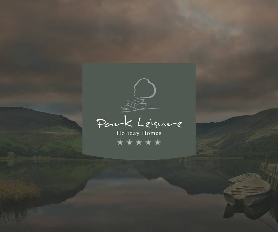 Scenic lake with boat and hills, cloudy sky, and a central overlay featuring 'Park Leisure Holiday Homes' logo with stars.