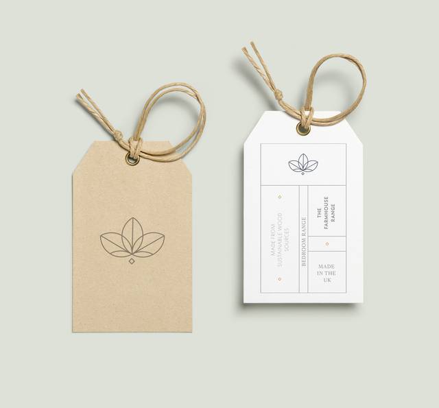 Two eco-friendly product tags with minimalistic leaf logo, one in beige and one in white, tied with natural twine against a pale green background.