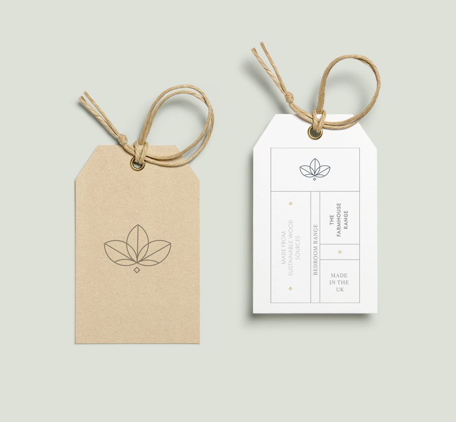 Two eco-friendly product tags with minimalistic leaf logo, one in beige and one in white, tied with natural twine against a pale green background.