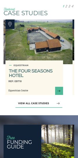 Aerial view of a large equestrian facility with multiple buildings, a riding arena, and surrounding green fields under a cloudy sky.