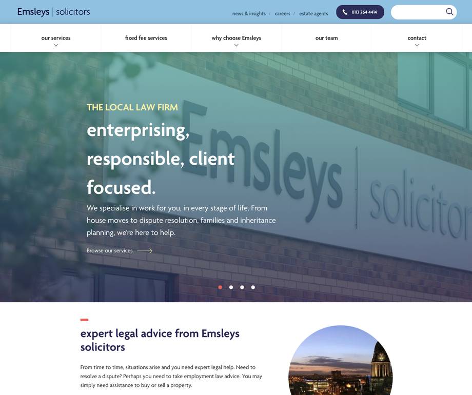 Exterior view of Emsleys solicitors office building with a large sign on the brick wall, taken during daytime.