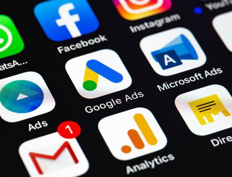 Smartphone screen displaying various social media, advertising, and analytics app icons including Facebook, Instagram, Google Ads, Microsoft Ads, and Gmail.