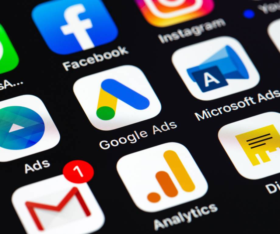 Smartphone screen displaying various social media, advertising, and analytics app icons including Facebook, Instagram, Google Ads, Microsoft Ads, and Gmail.