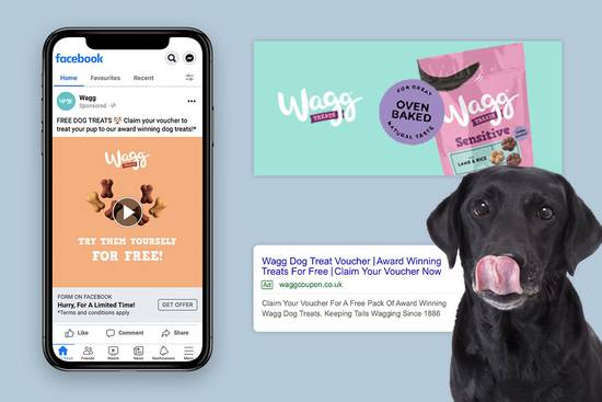 A black dog with its tongue out in front of a screen displaying a Facebook ad for free dog treats, alongside a promotional Wagg treat packet.