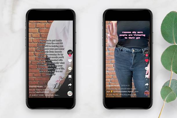 Two smartphones displaying TikTok videos about gut health and reasons to listen to your gut, with a brick wall background and green leaves beside.