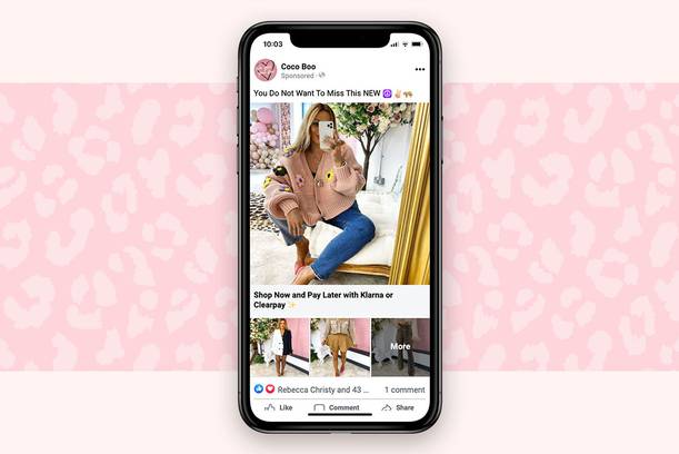 A woman taking a mirror selfie on her phone, sitting on a cream sofa with a floral backdrop and a gold curtain, surrounded by pink and neutral decor.